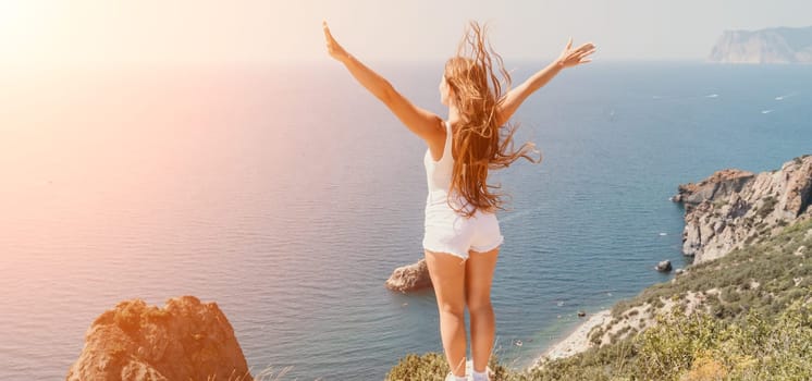 Woman travel sea. Young Happy woman in a long red dress posing on a beach near the sea on background of volcanic rocks, like in Iceland, sharing travel adventure journey