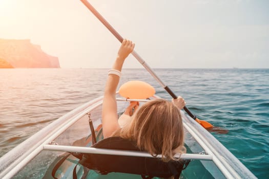 Woman in kayak back view. Happy young woman with long hair floating in transparent kayak on the crystal clear sea. Summer holiday vacation and cheerful female people having fun on the boat.