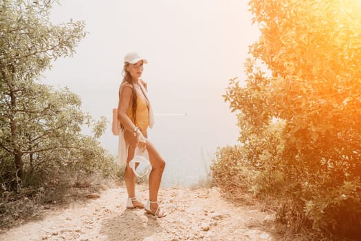 Woman travel sea. Happy tourist taking picture outdoors for memories. Woman traveler looks at the edge of the cliff on the sea bay of mountains, sharing travel adventure journey.