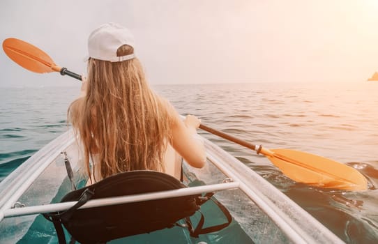 Woman in kayak back view. Happy young woman with long hair floating in transparent kayak on the crystal clear sea. Summer holiday vacation and cheerful female people having fun on the boat.