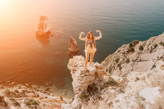 Woman travel sea. Happy tourist taking picture outdoors for memories. Woman traveler looks at the edge of the cliff on the sea bay of mountains, sharing travel adventure journey.