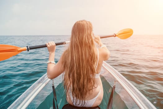 Woman in kayak back view. Happy young woman with long hair floating in transparent kayak on the crystal clear sea. Summer holiday vacation and cheerful female people having fun on the boat.