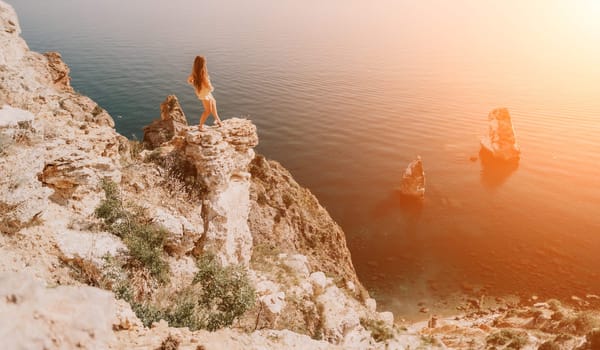 Woman travel sea. Happy tourist taking picture outdoors for memories. Woman traveler looks at the edge of the cliff on the sea bay of mountains, sharing travel adventure journey.