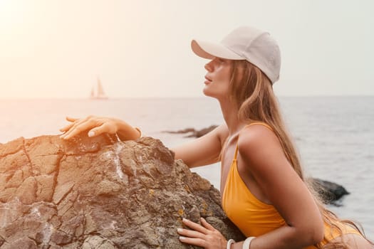 Woman travel sea. Young Happy woman in a long red dress posing on a beach near the sea on background of volcanic rocks, like in Iceland, sharing travel adventure journey