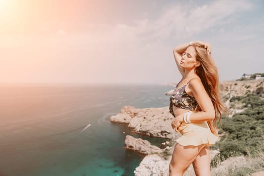 Woman travel sea. Happy tourist taking picture outdoors for memories. Woman traveler looks at the edge of the cliff on the sea bay of mountains, sharing travel adventure journey.