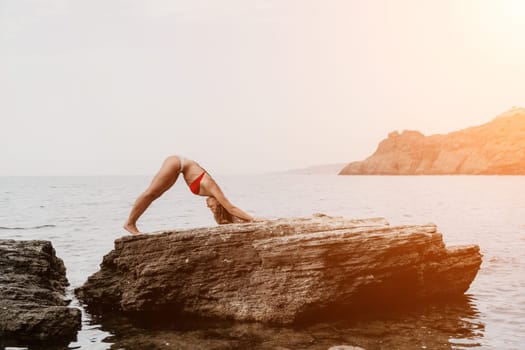 Woman meditating in yoga pose silhouette at the ocean, beach and rock mountains. Motivation and inspirational fit and exercising. Healthy lifestyle outdoors in nature, fitness concept.