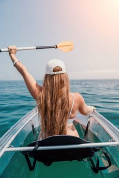 Woman in kayak back view. Happy young woman with long hair floating in transparent kayak on the crystal clear sea. Summer holiday vacation and cheerful female people having fun on the boat.