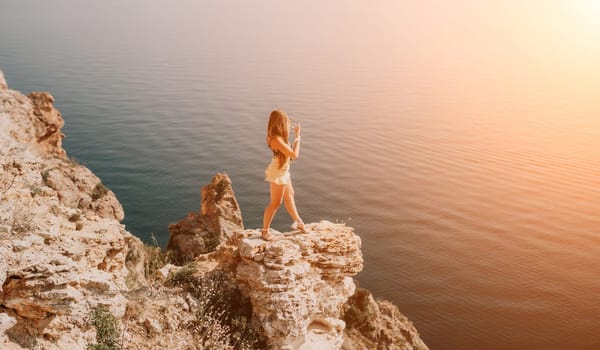 Woman travel sea. Happy tourist taking picture outdoors for memories. Woman traveler looks at the edge of the cliff on the sea bay of mountains, sharing travel adventure journey.