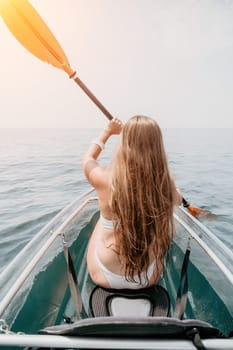 Woman in kayak back view. Happy young woman with long hair floating in transparent kayak on the crystal clear sea. Summer holiday vacation and cheerful female people having fun on the boat.