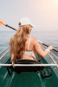 Woman in kayak back view. Happy young woman with long hair floating in transparent kayak on the crystal clear sea. Summer holiday vacation and cheerful female people having fun on the boat.