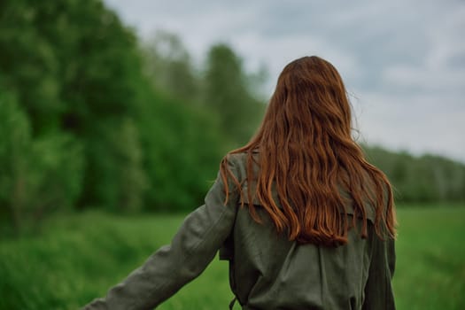 a woman with beautiful, well-groomed jumpy hair developing in the wind stands in a field. High quality photo