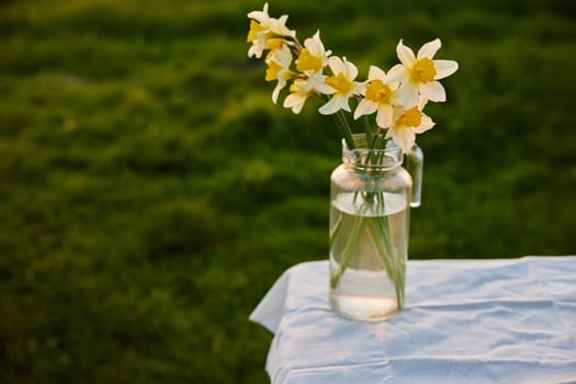 flowers in a vase stand outside during sunset on a table with a white tablecloth. High quality photo