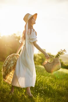 a woman in a long light dress walks through the countryside in a hat and with a basket in her hands in the rays of the setting sun enjoying nature. High quality photo