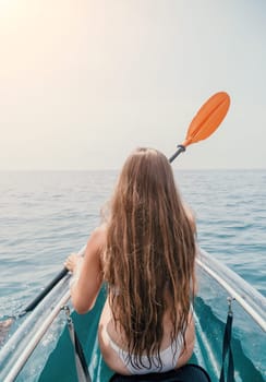 Woman in kayak back view. Happy young woman with long hair floating in transparent kayak on the crystal clear sea. Summer holiday vacation and cheerful female people having fun on the boat.