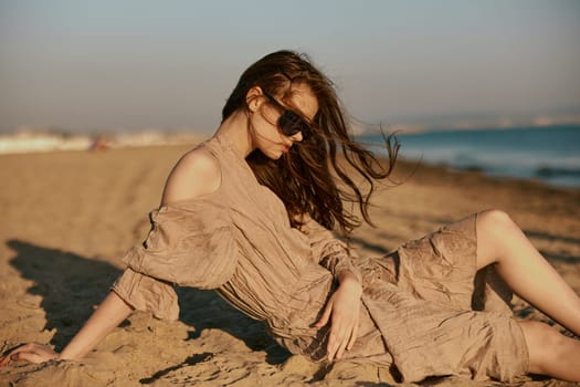 sophisticated red-haired woman in sunglasses lies on the sea coast in windy weather. High quality photo