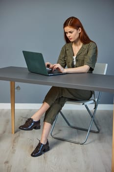 very pensive woman in overalls sits at a laptop in the office working. High quality photo