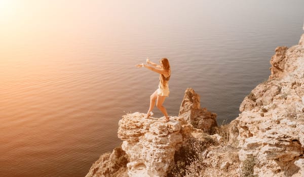 Woman travel sea. Happy tourist taking picture outdoors for memories. Woman traveler looks at the edge of the cliff on the sea bay of mountains, sharing travel adventure journey.