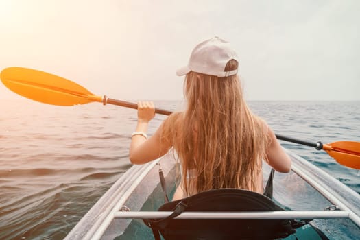 Woman in kayak back view. Happy young woman with long hair floating in transparent kayak on the crystal clear sea. Summer holiday vacation and cheerful female people having fun on the boat.