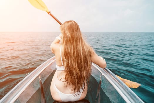 Woman in kayak back view. Happy young woman with long hair floating in transparent kayak on the crystal clear sea. Summer holiday vacation and cheerful female people having fun on the boat.