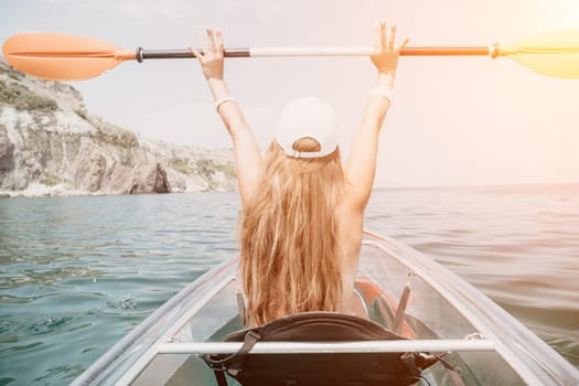 Woman in kayak back view. Happy young woman with long hair floating in transparent kayak on the crystal clear sea. Summer holiday vacation and cheerful female people having fun on the boat.