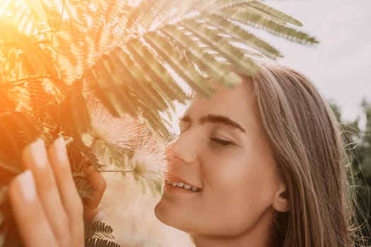 Beauty portrait of young woman closeup. Young girl smelling Chinese acacia pink blossoming flowers. Portrait of young woman in blooming spring, summer garden. Romantic vibe. Female and nature.