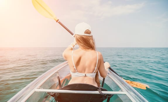 Woman in kayak back view. Happy young woman with long hair floating in transparent kayak on the crystal clear sea. Summer holiday vacation and cheerful female people having fun on the boat.