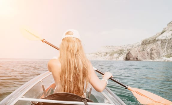 Woman in kayak back view. Happy young woman with long hair floating in transparent kayak on the crystal clear sea. Summer holiday vacation and cheerful female people having fun on the boat.