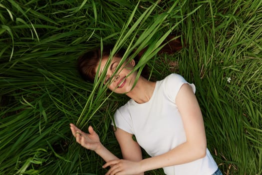 happy woman lies in tall grass covering her face with leaves. High quality photo