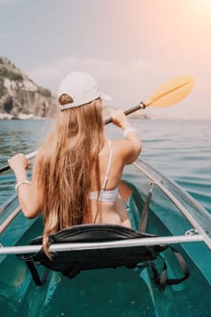 Woman in kayak back view. Happy young woman with long hair floating in transparent kayak on the crystal clear sea. Summer holiday vacation and cheerful female people having fun on the boat.