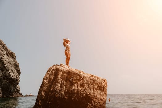 Woman meditating in yoga pose silhouette at the ocean, beach and rock mountains. Motivation and inspirational fit and exercising. Healthy lifestyle outdoors in nature, fitness concept.