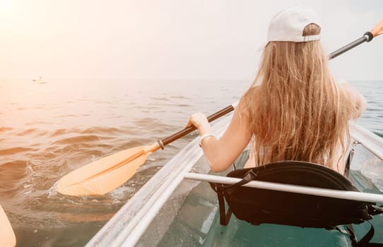 Woman in kayak back view. Happy young woman with long hair floating in transparent kayak on the crystal clear sea. Summer holiday vacation and cheerful female people having fun on the boat.