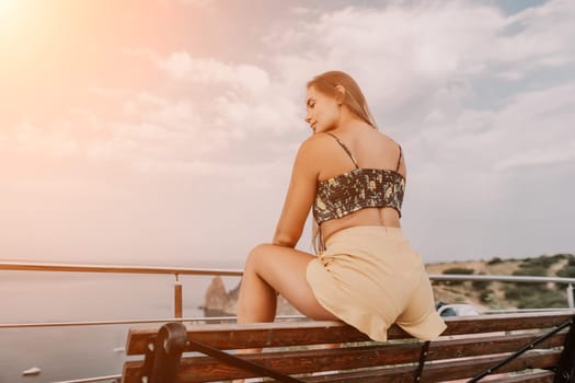 Woman travel sea. Happy tourist taking picture outdoors for memories. Woman traveler looks at the edge of the cliff on the sea bay of mountains, sharing travel adventure journey.