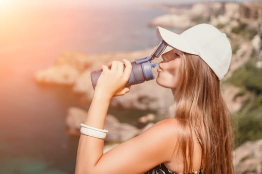 Woman travel sea. Happy tourist taking picture outdoors for memories. Woman traveler looks at the edge of the cliff on the sea bay of mountains, sharing travel adventure journey.