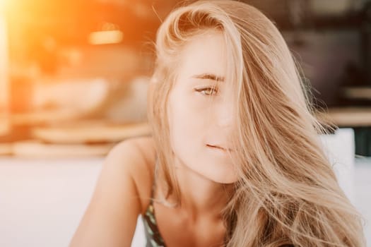 Happy woman portrait in cafe. Boho chic fashion style. Outdoor photo of young happy woman with long hair, sunny weather outdoors sitting in modern cafe