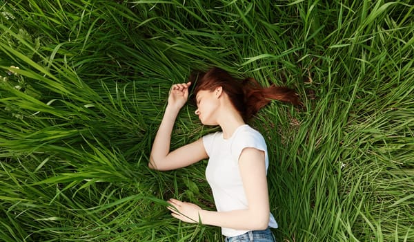 serene, woman lies in green tall grass in casual clothes. High quality photo