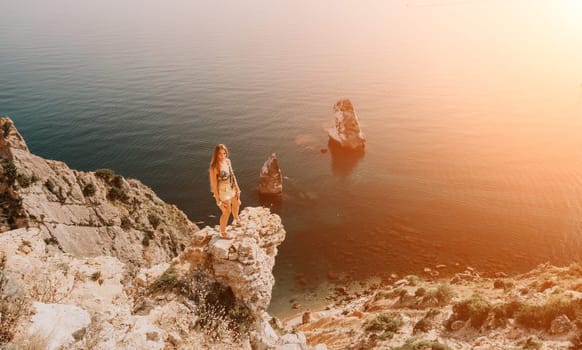 Woman travel sea. Happy tourist taking picture outdoors for memories. Woman traveler looks at the edge of the cliff on the sea bay of mountains, sharing travel adventure journey.