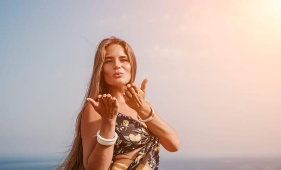 Woman travel sea. Happy tourist taking picture outdoors for memories. Woman traveler looks at the edge of the cliff on the sea bay of mountains, sharing travel adventure journey.