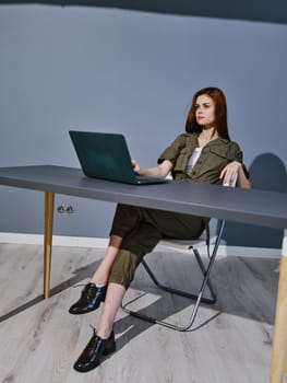 woman working on a laptop while sitting in a room at a table. High quality photo