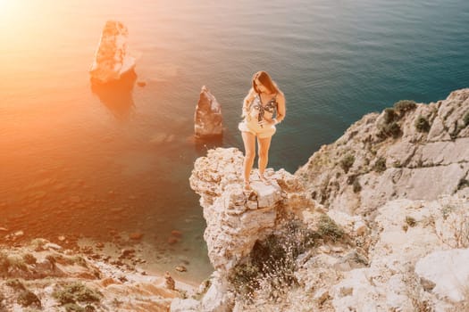 Woman travel sea. Happy tourist taking picture outdoors for memories. Woman traveler looks at the edge of the cliff on the sea bay of mountains, sharing travel adventure journey.