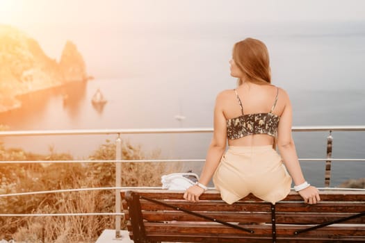 Woman travel sea. Happy tourist taking picture outdoors for memories. Woman traveler looks at the edge of the cliff on the sea bay of mountains, sharing travel adventure journey.