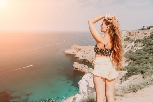 Woman travel sea. Happy tourist taking picture outdoors for memories. Woman traveler looks at the edge of the cliff on the sea bay of mountains, sharing travel adventure journey.