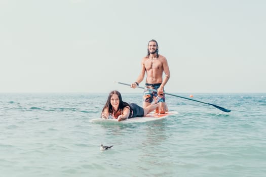 Silhouette of woman standing, surfing on SUP board, confident paddling through water surface. Idyllic sunset or sunrise. Sports active lifestyle at sea or river.