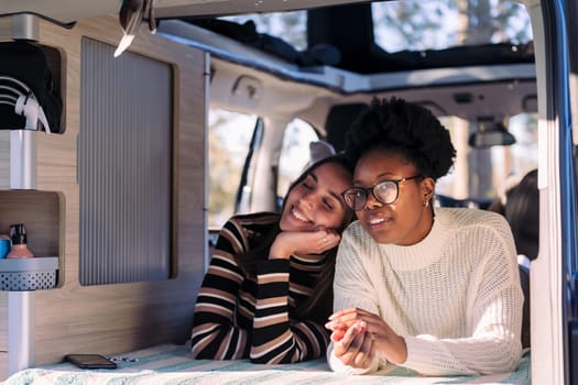 two adventurous young women relaxing in a camper van, concept of weekend getaway with friend and van life relaxation