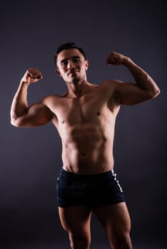 Handsome muscular shirtless young man standing confident, front view, looking at the camera