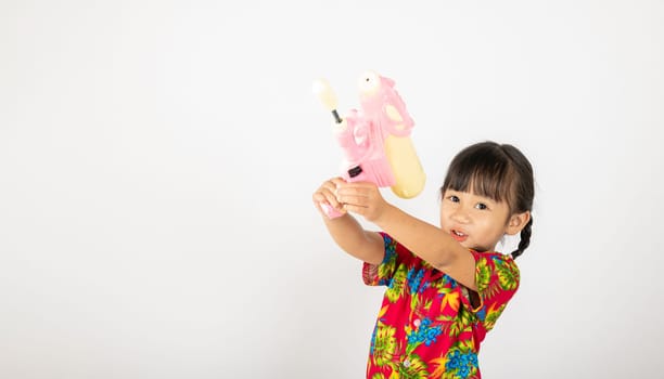 Happy Songkran Day, Asian kid girl with floral shirt hold water gun, Thai child funny hold toy water pistol and smile, isolated on white background, Thailand Songkran festival national culture concept