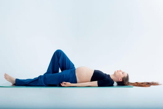 Pleasant pregnant woman posing in profile and trying yoga Young happy expectant relaxing, thinking about her baby and enjoying her future life. Motherhood, pregnancy, yoga concept.