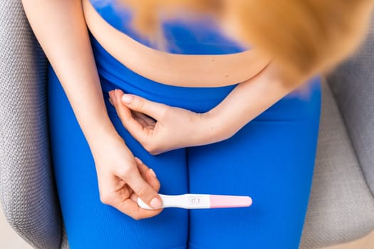 Top view on the woman holding a pregnancy test in her hands.