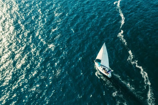 ROVINJ, CZECH REPUBLIC - JULY 03 2021: Sailing vessel leaves white foam trace on surface of Adriatic sea. Bright sunlight reflecting from surface of calm sea rippling water. Aerial view