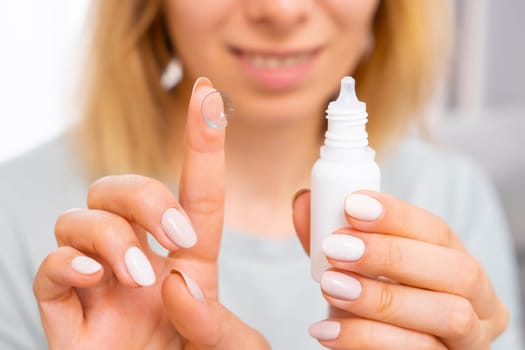 Woman holding eye lens on the finger and eye drops. Medicine and eye care concept.