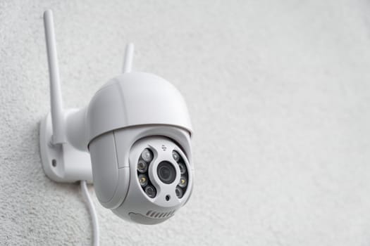 Round CCTV camera with antennas shoots video on the white wall. Digital equipment to record and broadcast real time video closeup